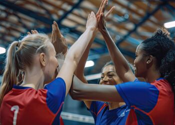 Salonda sevinçle ellerini yukarıda birleştiren kadın voleybolcular.