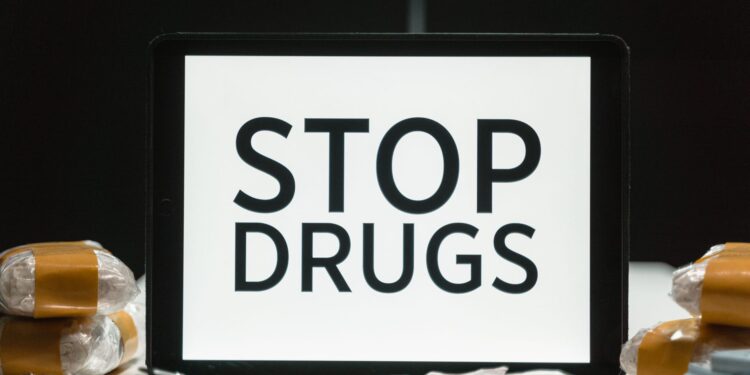 Üzerinde uyuşturucuyla mücadele mesajı yazan tablet bilgisayar ve uyuşturucu maddeler.