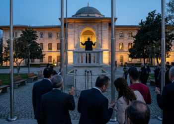 Açık havada bir balkonda konuşma yapan siyasetçiyi dinleyen kalabalık.