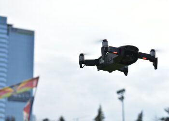 Açık havada uçan, pervaneleri dönen siyah renkli profesyonel bir drone.