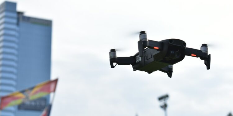 Açık havada uçan, pervaneleri dönen siyah renkli profesyonel bir drone.