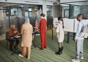 Ofis ortamındaki seçim sandıklarında oy vermek için sıraya giren insanlar.