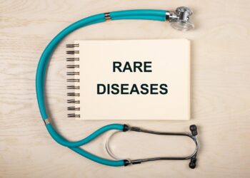 Ahşap masanın üzerinde 'Rare Diseases' yazılı not defteri ve stetoskop.