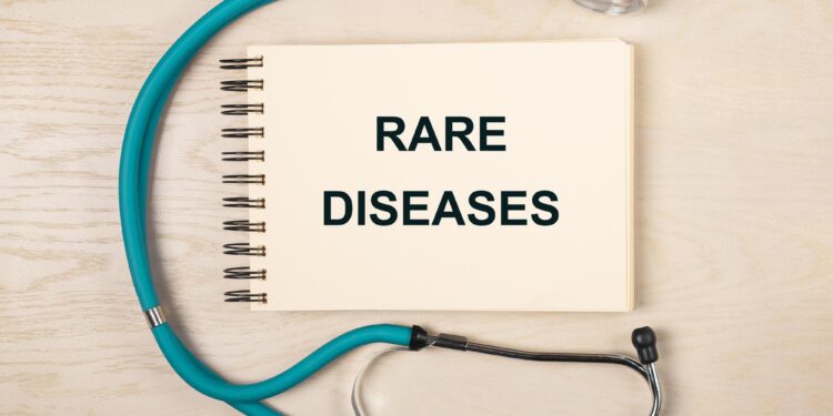Ahşap masanın üzerinde 'Rare Diseases' yazılı not defteri ve stetoskop.