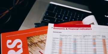 Bilgisayar klavyesi üzerinde ekonomik ve finansal göstergeleri içeren basılı raporlar bulunuyor.