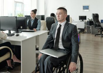 Ofis ortamında tekerlekli sandalyede oturan takım elbise giymiş memur adayı.