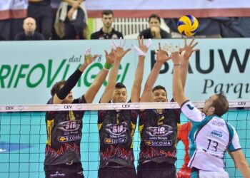File önünde smaç vuran voleybolcular ve yükselen sarı mavi voleybol topu.