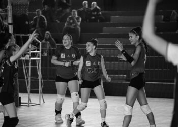 Siyah beyaz fotoğrafta sevinç yaşayan ve birbirine sarılan kadın voleybolcular.