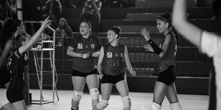 Siyah beyaz fotoğrafta sevinç yaşayan ve birbirine sarılan kadın voleybolcular.
