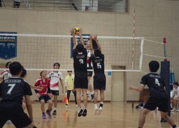Salon voleybolu maçında file üzerinde yükselen sporcuların blok yapma anı.