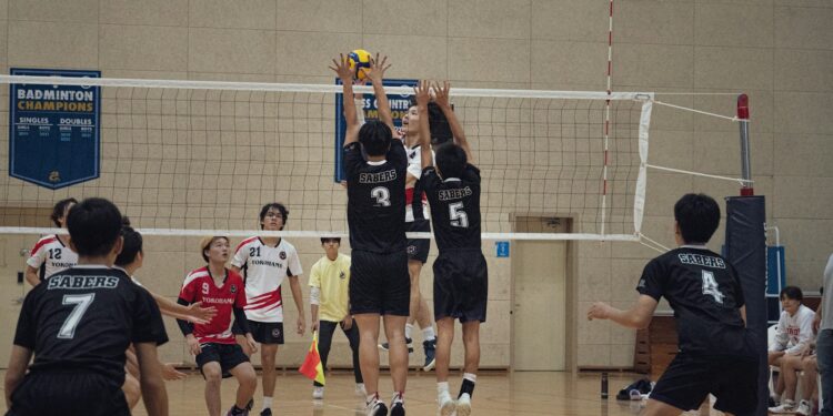 Salon voleybolu maçında file üzerinde yükselen sporcuların blok yapma anı.