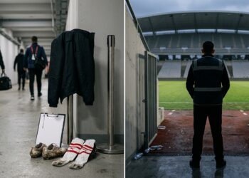 Futbol stadyumunun tünelinde yürüyen teknik heyet ve sahaya bakan görevli.