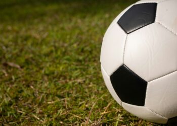 Çim saha üzerinde duran siyah beyaz klasik futbol topu.
