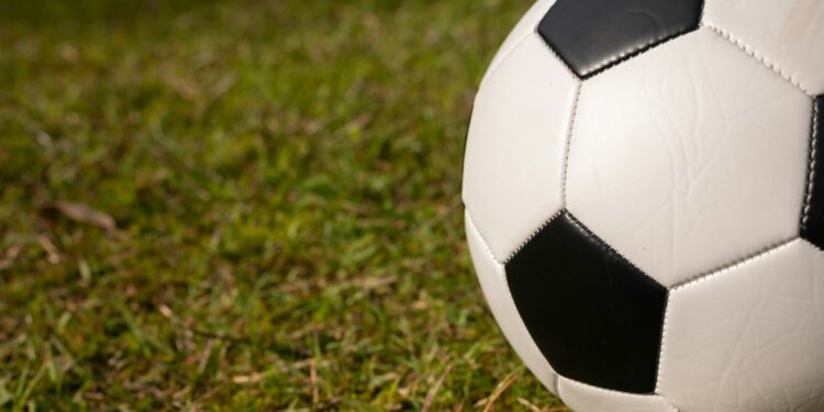 Çim saha üzerinde duran siyah beyaz klasik futbol topu.