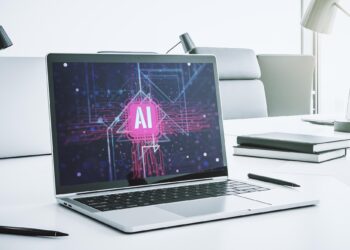 Açık bir dizüstü bilgisayarın ekranında pembe renkli büyük bir yapay zeka logosu parlıyor.