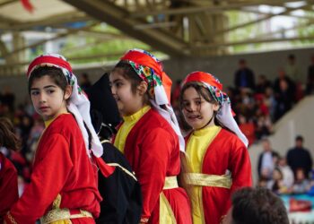 Kırmızı geleneksel kıyafetler giymiş halk oyunları oynayan genç kızlar.