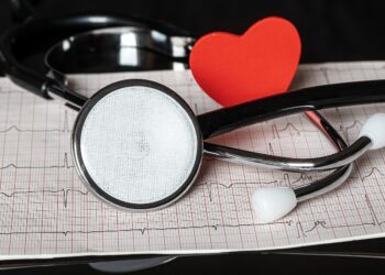Stetoskop, kırmızı kalp figürü ve EKG kağıdı yer alıyor.