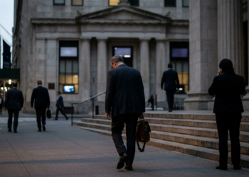 New York'ta Wall Street civarındaki bir binanın merdivenlerinde yürüyen takım elbiseli iş insanları.