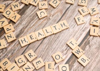 Ahşap masa üzerinde Scrabble taşlarıyla oluşturulmuş English 'HEALTH' yazısı.