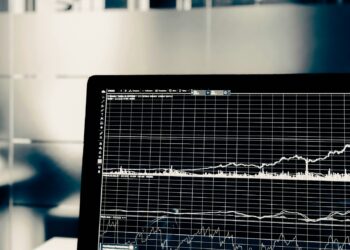 Bilgisayar ekranında beyaz renkli grafik çizgileri ve finansal veriler bulunuyor.