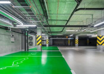 Yeşil renkli işaretlemeleri ve borulama sistemleri olan modern kapalı otopark.